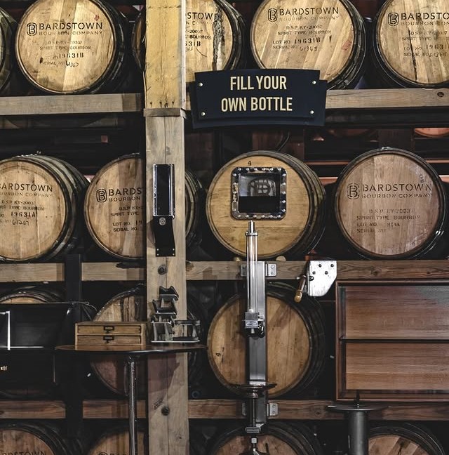 Bardstown Bourbon Company barrels stacked with a “Fill Your Own Bottle” station in front.