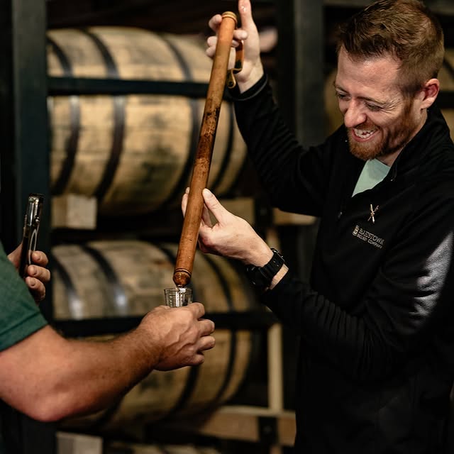 A Bardstown Bourbon Company guides thieving bourbon straight from the barrel for a tasting.